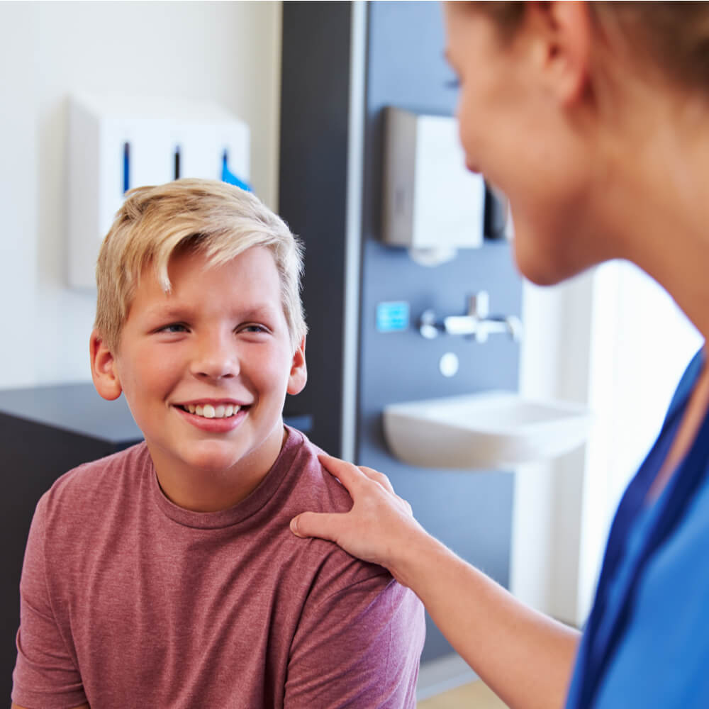 Teenage Boy Being Reassured By Doctor In Hospital Room
